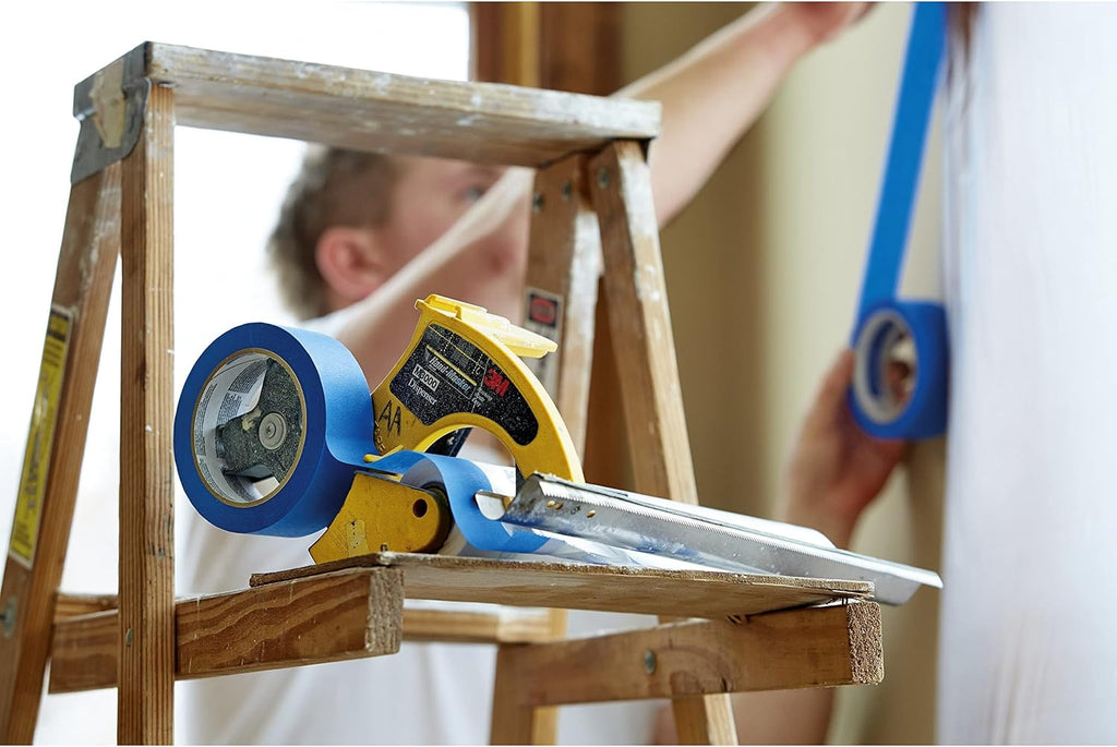 Painter on ladder using 3M Hand-Masker tool for window protection