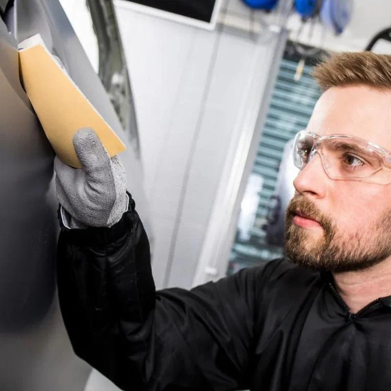 Tradie using Mirka Goldflex Soft for dry sanding a car panel in a workshop