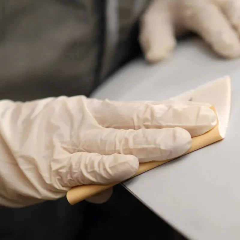 Hand sanding delicate curves with a flexible Mirka abrasive sheet and gloves