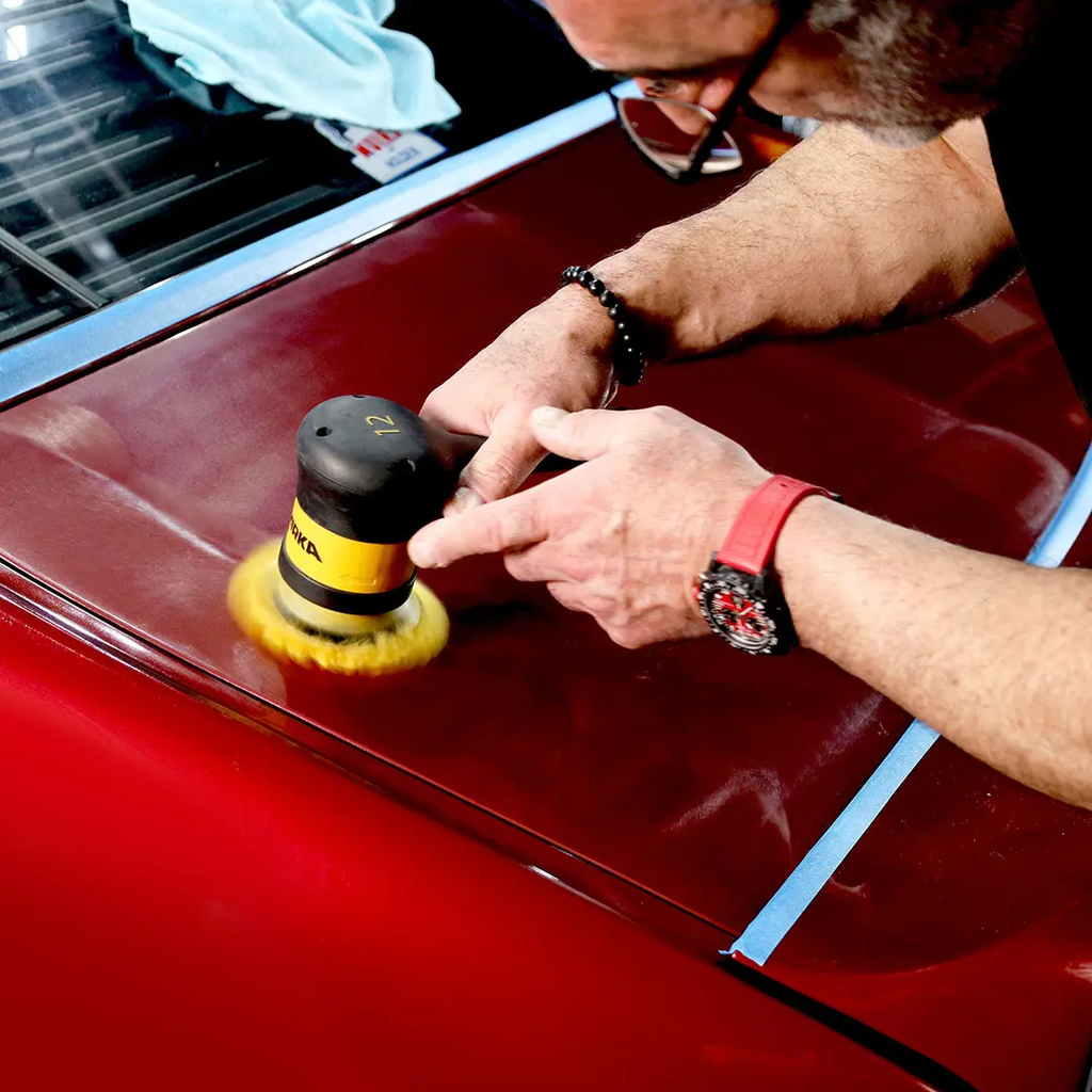 Tradie using a cordless Mirka orbital polisher with a yellow wool pad on a red car bonnet