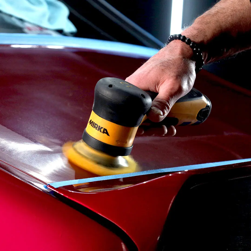 Tradie using a cordless Mirka orbital polisher with a yellow wool pad on a red car bonnet