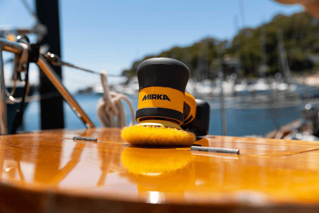 Mirka AROP-B cordless polisher with a wool pad resting on a polished timber yacht deck