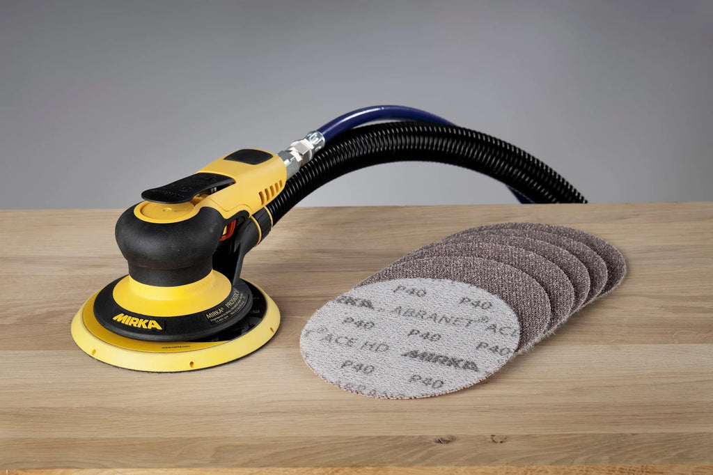 Mirka PROS 650CV pneumatic sander shown with a selection of Abranet Ace net abrasives