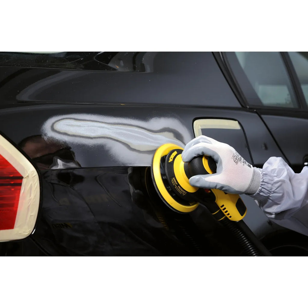 Professional sanding a black car panel with the Mirka PROS 650CV pneumatic orbital sander