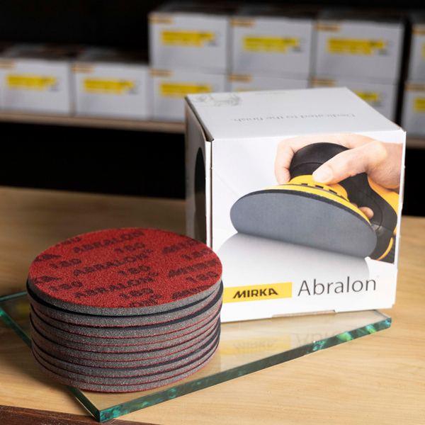 Stack of red Abralon foam discs next to a box for high-gloss timber finish refinement