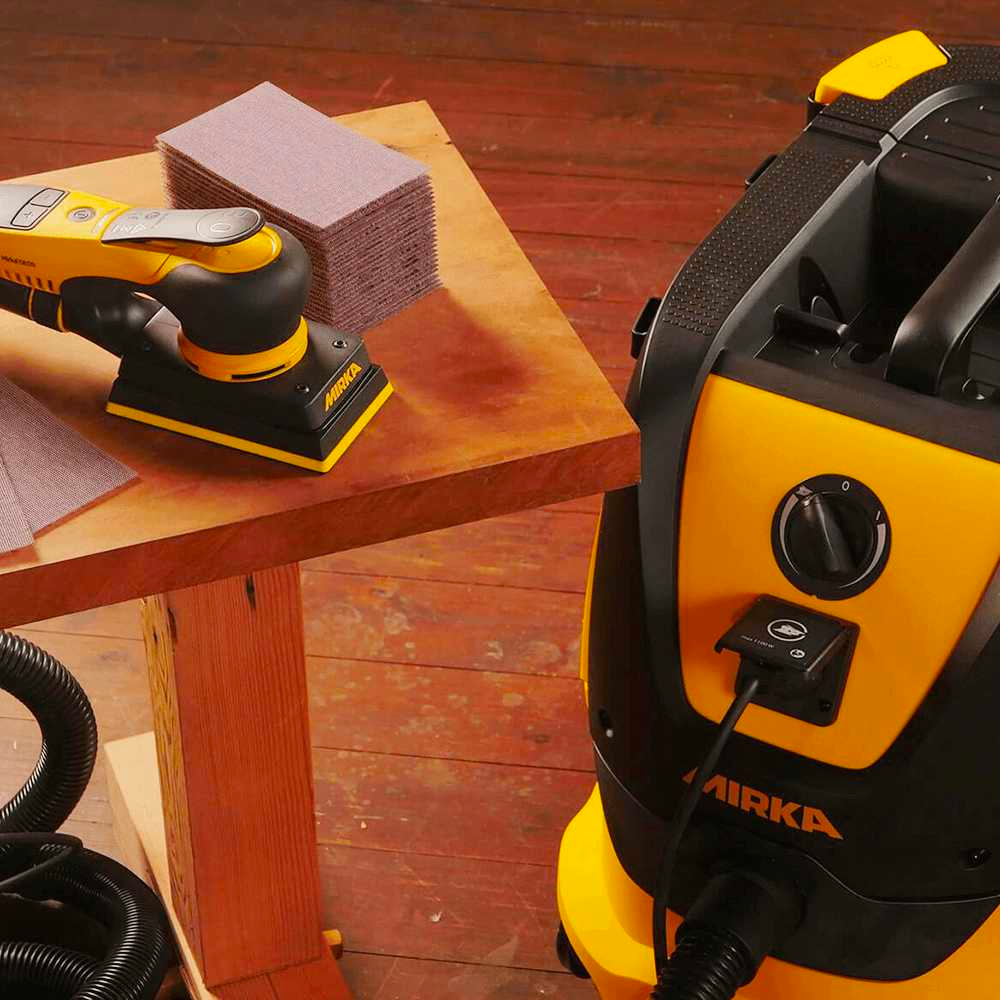 Mirka DEOS sander and Abranet Ace sheets on a timber workbench connected to an extractor