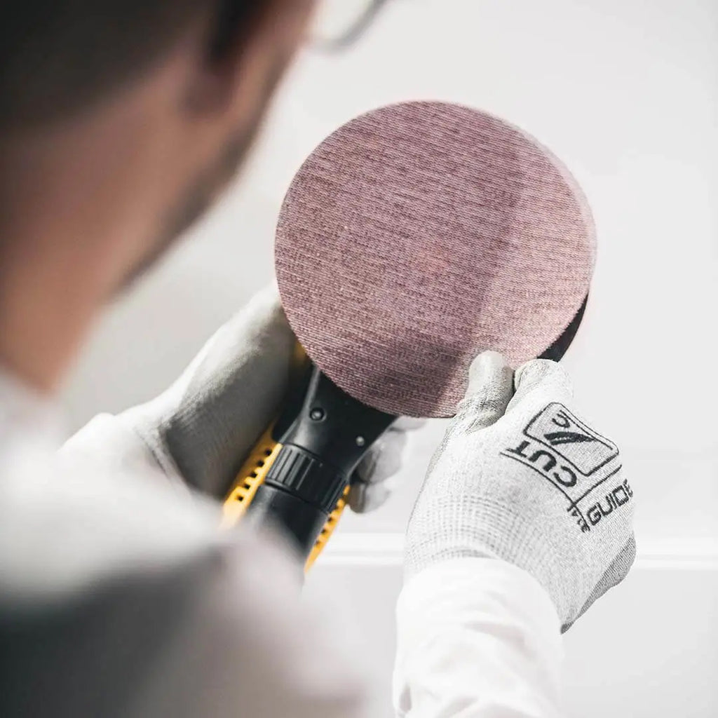 Professional using a 125mm Abranet Ace net abrasive disc on a white surface for a smooth finish