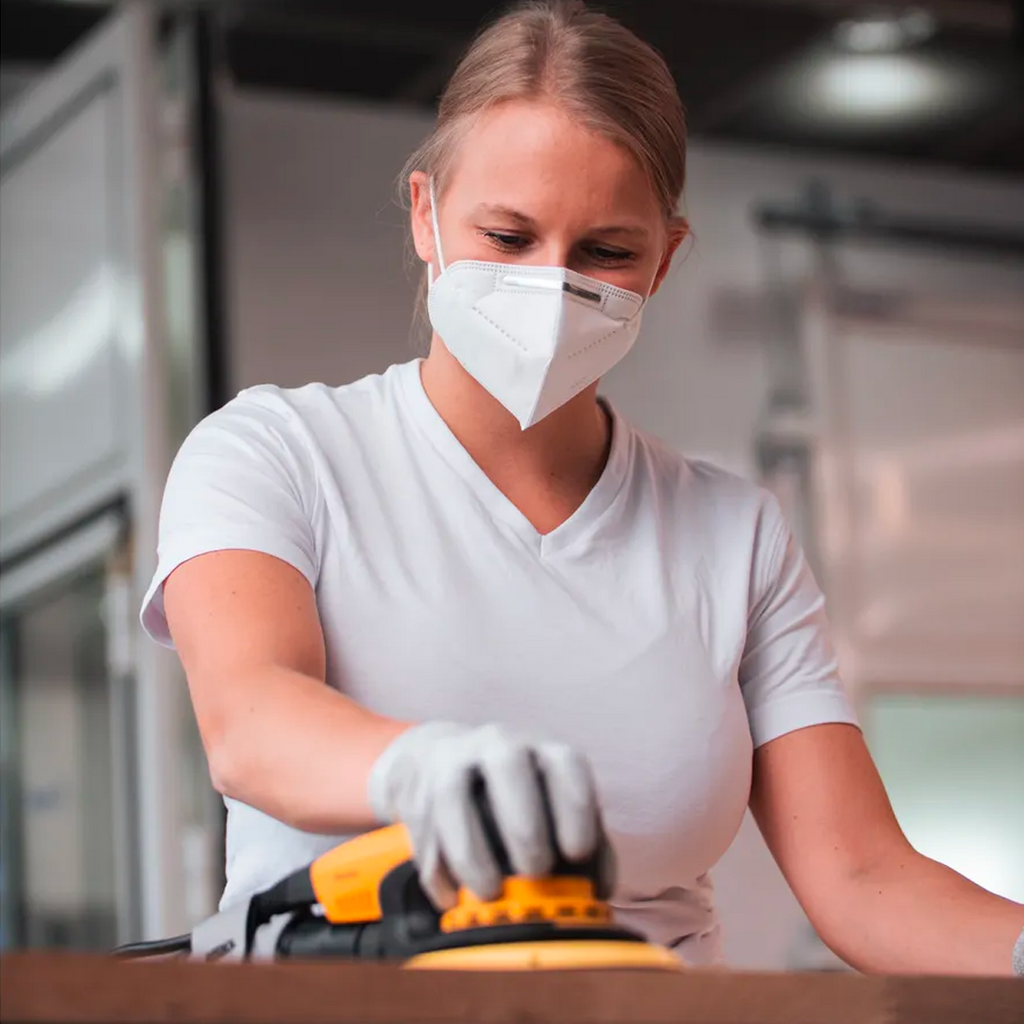 Tradie wearing a respirator while sanding a large timber surface with Abranet Ace