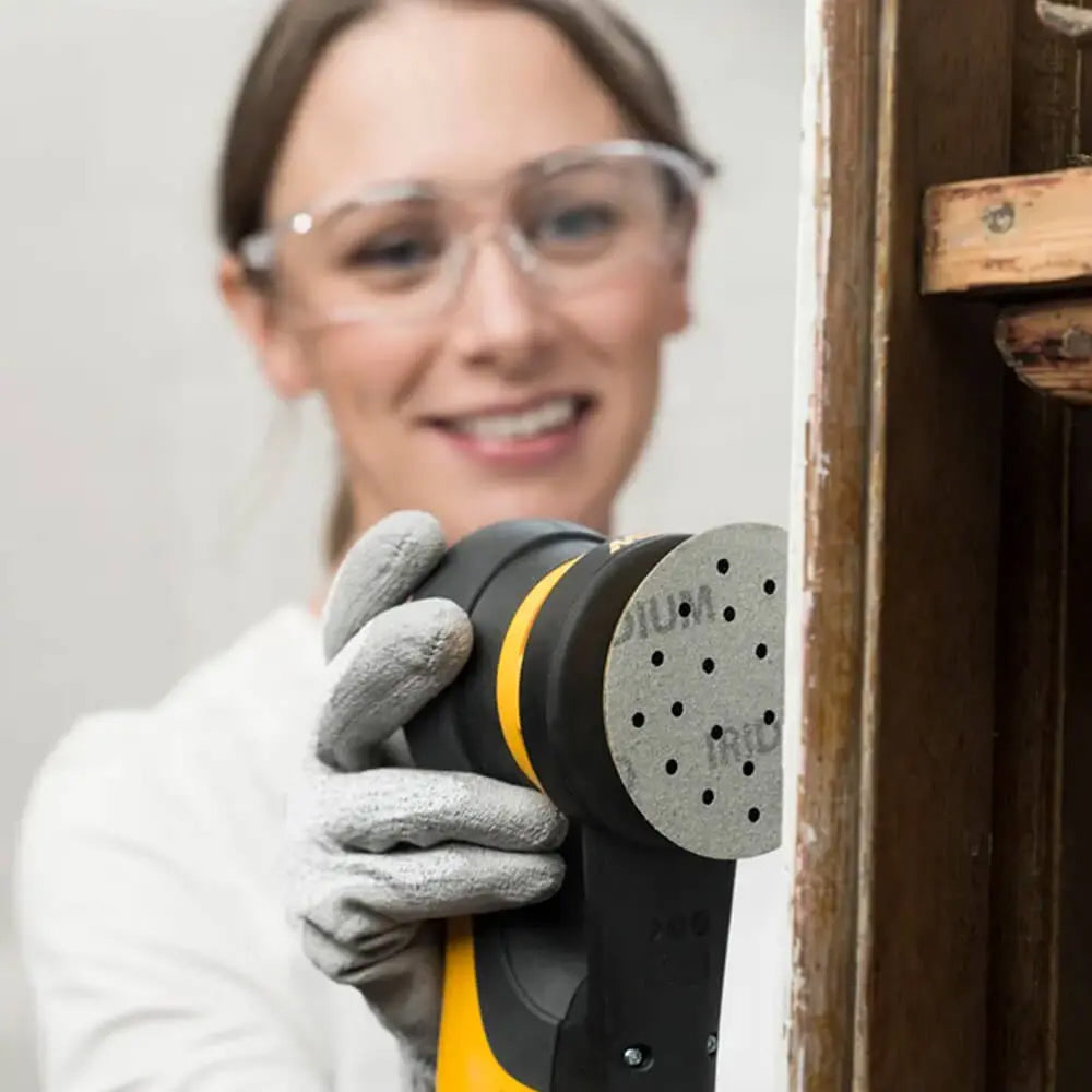 Female tradie using the ergonomic Mirka DEROS II for detailed timber furniture restoration