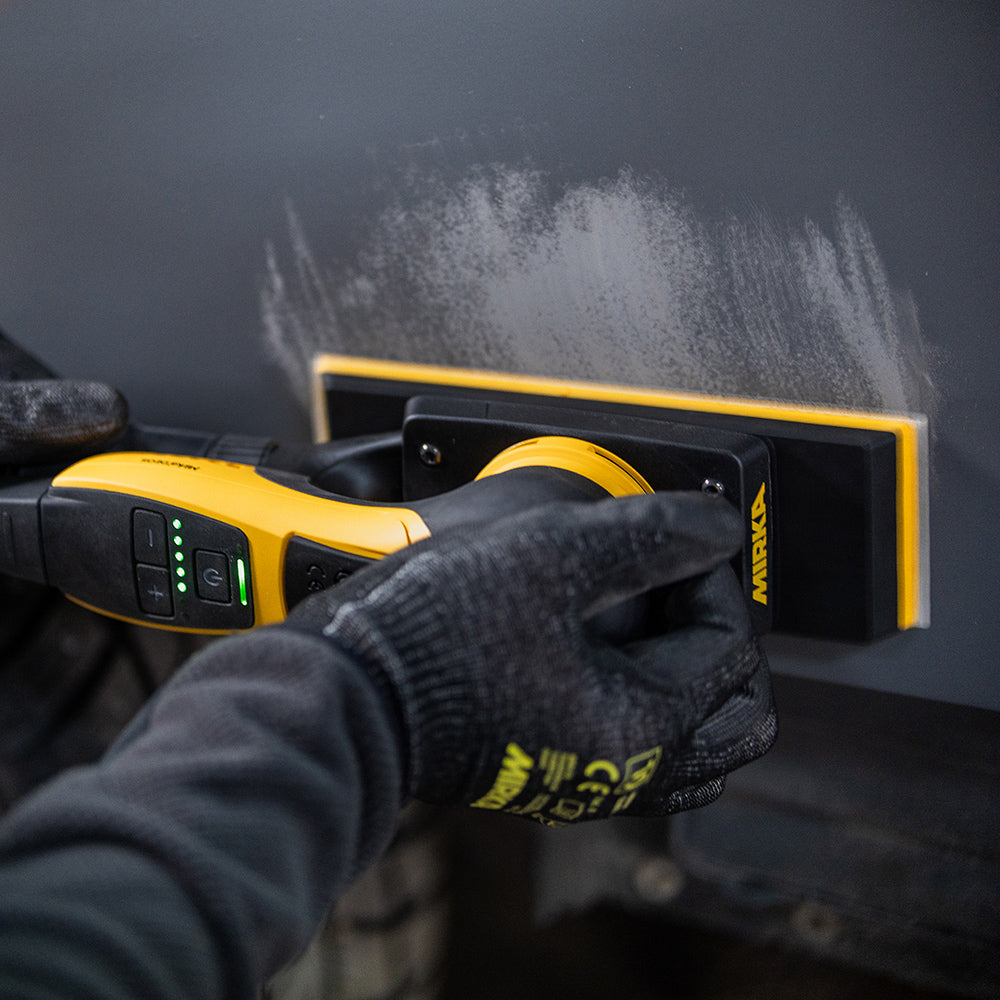 Tradie using a Mirka DEOS II 383CV for precision sanding on a dark grey car body panel
