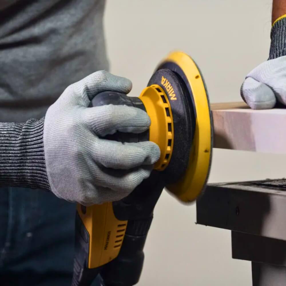 Tradie using Mirka DEROS II sander to finish a timber benchtop in a workshop