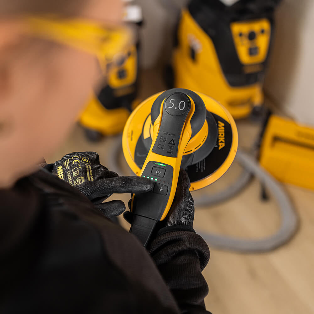 Professional adjusting the speed on a Mirka DEROS II 750 during high-performance sanding