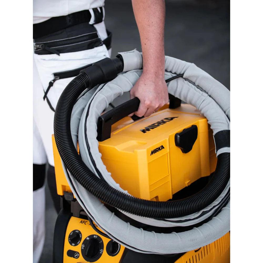 Tradie carrying a Mirka storage case with a sleeved extraction hose for on-site work