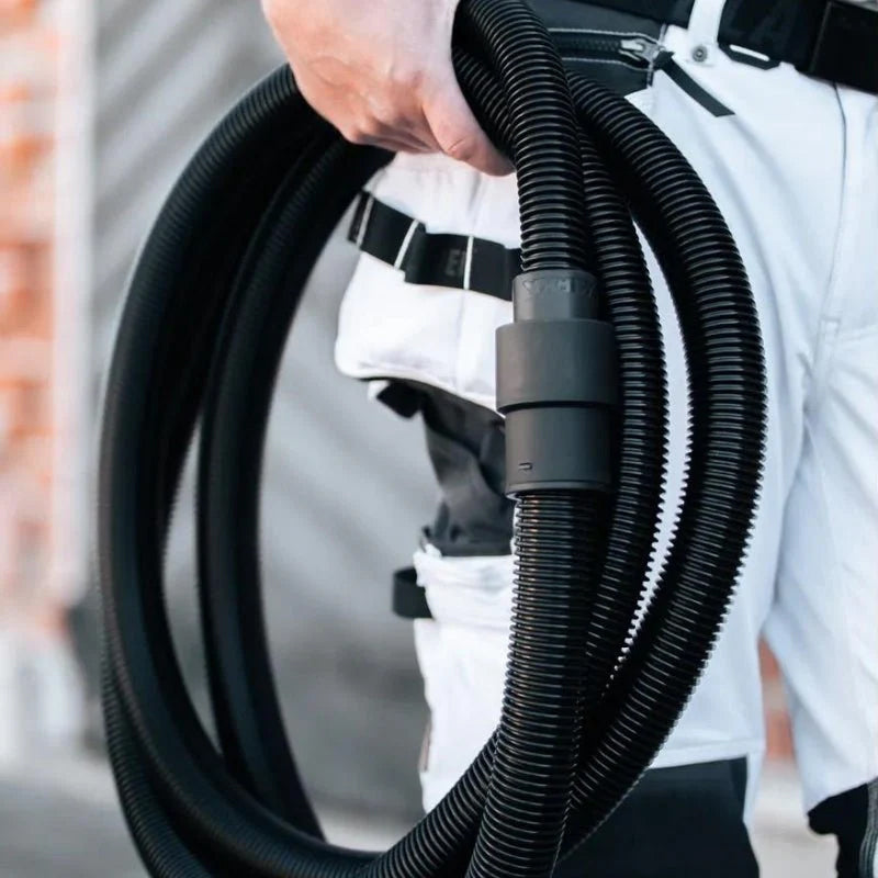 Tradie carrying a coiled 4m Mirka anti-static hose for mobile dust extraction
