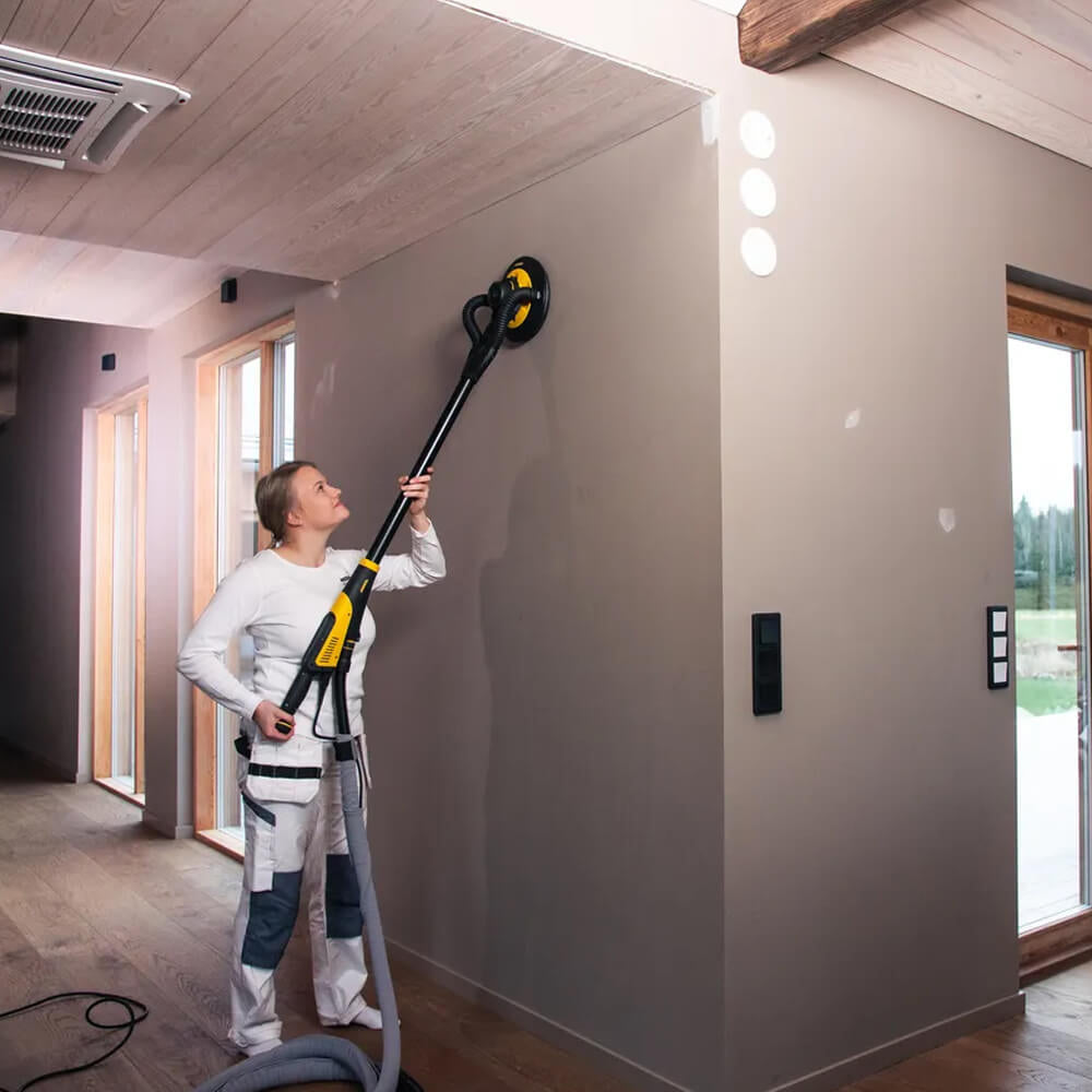 Female tradie effortlessly sanding a plasterboard wall with the lightweight Mirka LEROS