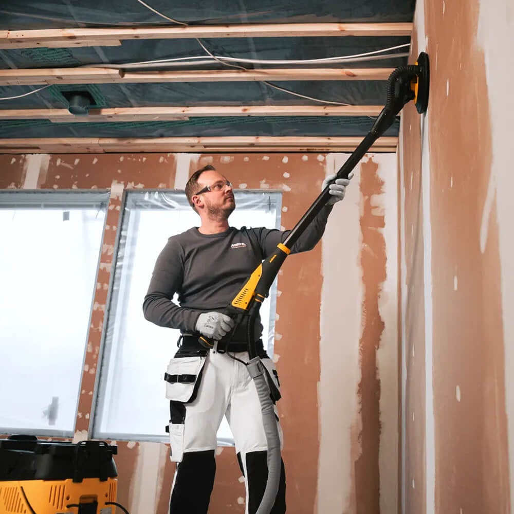 Professional tradie using Mirka LEROS 950CV for dust-free ceiling sanding on-site