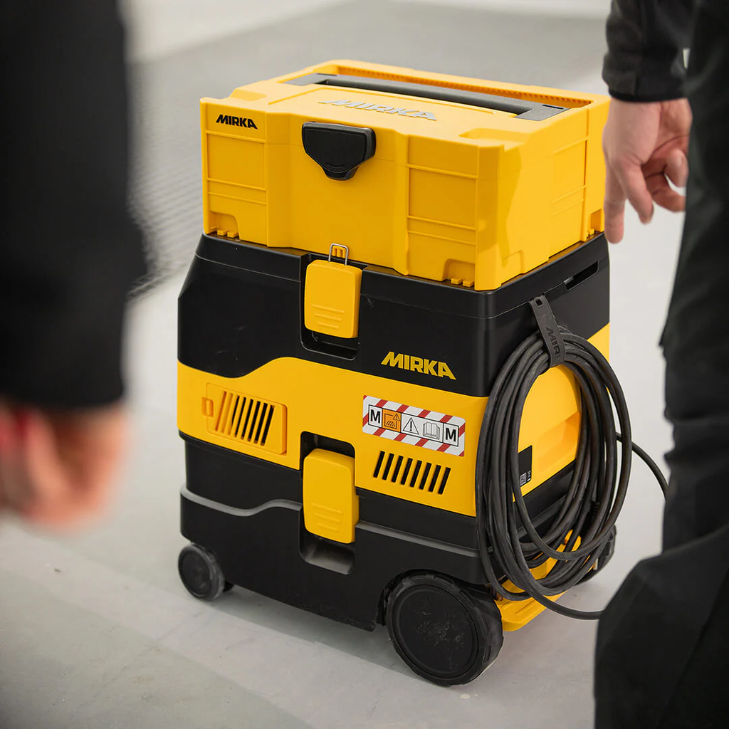 Mirka DEXOS M-class dust extractor stacked with yellow tool case for transport